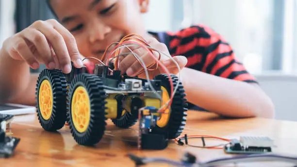 Photo of Concentrated boy creating robot at lab.