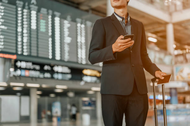 istock Young businessman at timetable screen board using smart phone.Flight board. 1176480891