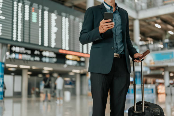 Young businessman at timetable screen board using smart phone.Flight board. stock photo