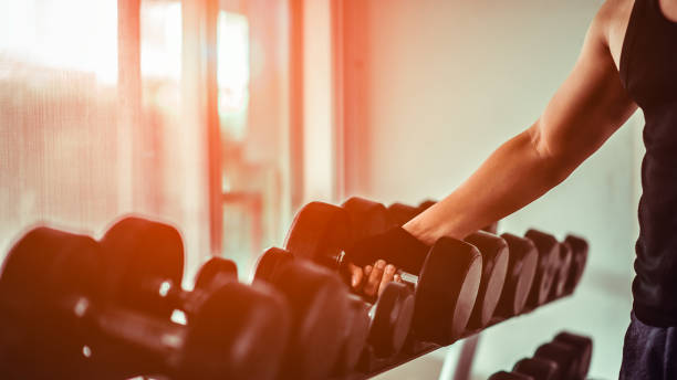 chiudi molti manubri metallici su rack in palestra. atleta in palestra allenarsi con manubri. mani con manubri. - health club social gathering exercising sport foto e immagini stock