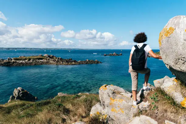 Rear view of middle-aged woman hiking and enjoying the view of the ocean in the Island of Batz