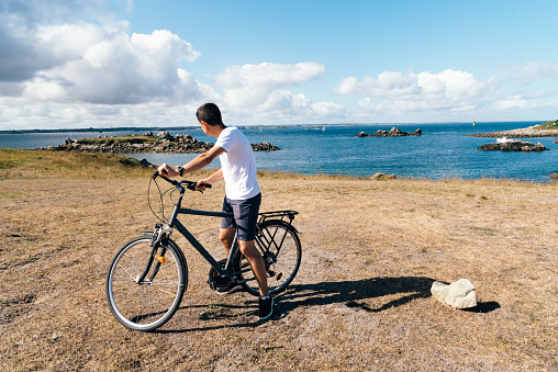 Attractive young male rides bicycle enjoying the views of landscape in the Island of Batz