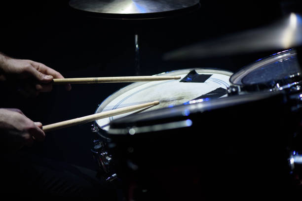istock man plays musical percussion instrument with sticks closeup on a black background, a musical concept with the working drum, beautiful lighting on the stage 1176487333