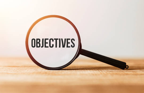 istock Magnifying glass with text Objectives on wooden table. 1176487542