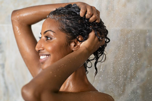 Woman bathing and washing hair Woman washing hair showering in bathroom at home. Smiling black woman bathing while looking away. Happy woman rinsing hair while taking a shower at luxury spa. washing hair stock pictures, royalty-free photos & images