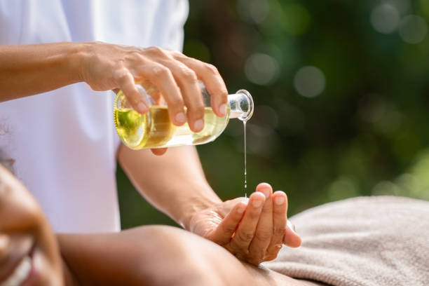 Masseuse hands pouring massage oil Closeup of masseuse hands pouring aroma oil on woman back. Woman prepare to do oriental spa massage for relaxing treatment. Therapist doing aromatherapy oil massage on girl body. Body care concept. massage oil photos stock pictures, royalty-free photos & images