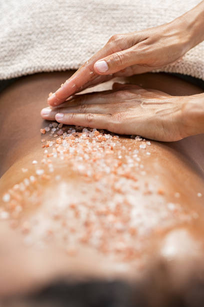 donna che applica sale di roccia sulla schiena - spa treatment health spa massage therapist women foto e immagini stock