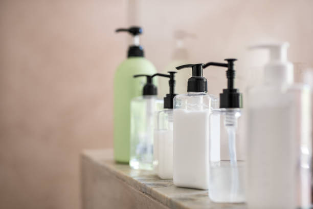Dispenser bottles of moisturizer at spa Dispenser bottles in a row kept on rack in bathroom. Close up of multiple shampoo, soap and body lotion bottles on marble at spa. Bottle of soap and liquid in bathroom. shower gel stock pictures, royalty-free photos & images