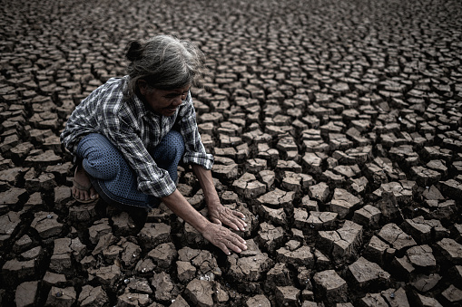 Elderly women are sitting looking at their hands, touching the ground in dry weather, global warming, selected focus.