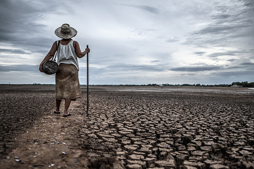 Women standing on dry soil and fishing gear, global warming and water crisis