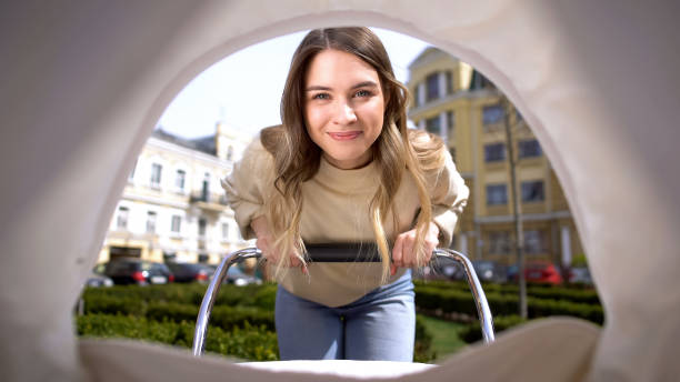 piękna uśmiechnięta matka podziwiająca wózek kołyszący się dla dziecka, macierzyństwo niemowlę pov - baby toddler young women outdoors zdjęcia i obrazy z banku zdjęć