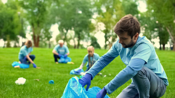 istock Male volunteer picking up litter and smiling on camera, eco project, activists 1176496227