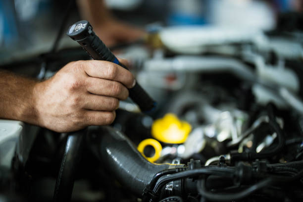 istock Close up of a mechanic examining car engine with a lamp. 1176496254