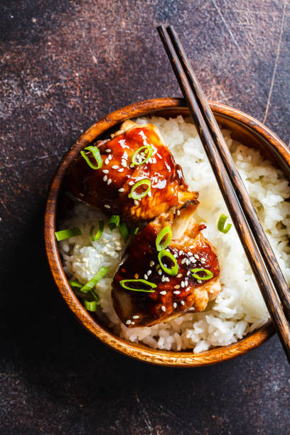 Teriyaki chicken with rice in a wooden bowl Teriyaki chicken with rice in a wooden bowl, dark background sticky sesame chicken sauces stock pictures, royalty-free photos & images