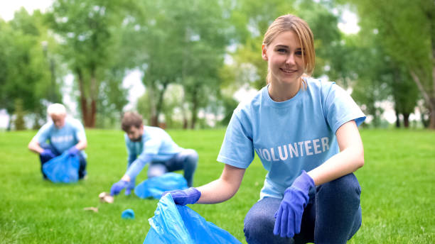 istock Pretty smiling female collecting forest garbage, looking at camera, volunteering 1176496354