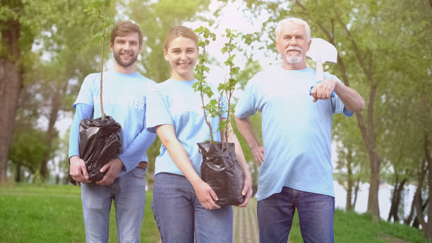 istock Smiling eco activists holding tree saplings and shovel in hands, reforestation 1176496367