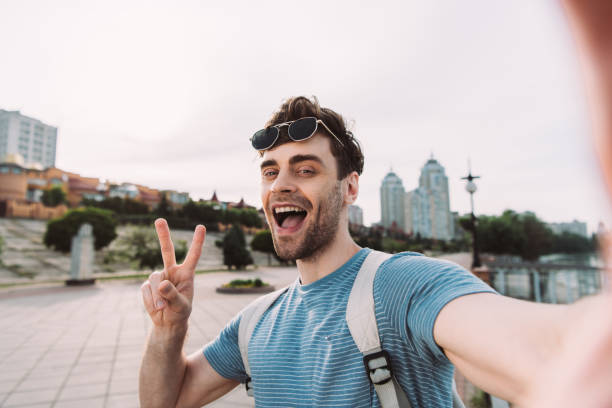 istock handsome man with glasses showing peace sign and taking selfie 1176496463