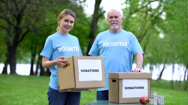 istock Joyful volunteers holding donation boxes in park smiling on camera, altruism 1176496718