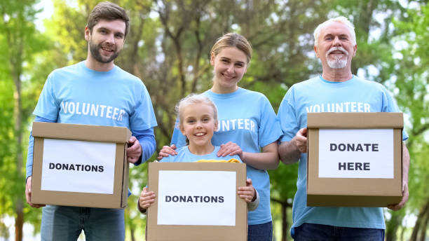 istock Smiling volunteers holding donation boxes looking camera, charity project, help 1176496763