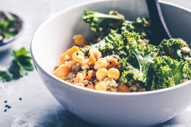 guiso vegano con garbanzos, batata y col rizada en tazón blanco. - quinoa spoon wood photography fotografías e imágenes de stock