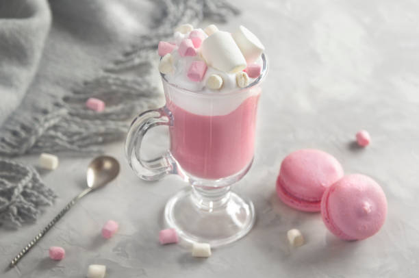 Pink hot chocolate with whipped cream and marshmallows. Macaroons on the grey background stock photo