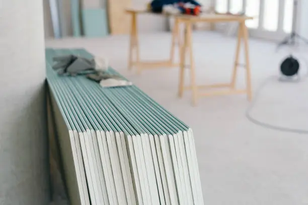 White chip board stacked against the wall inside a new build house with work table visible in the background in a spacious room