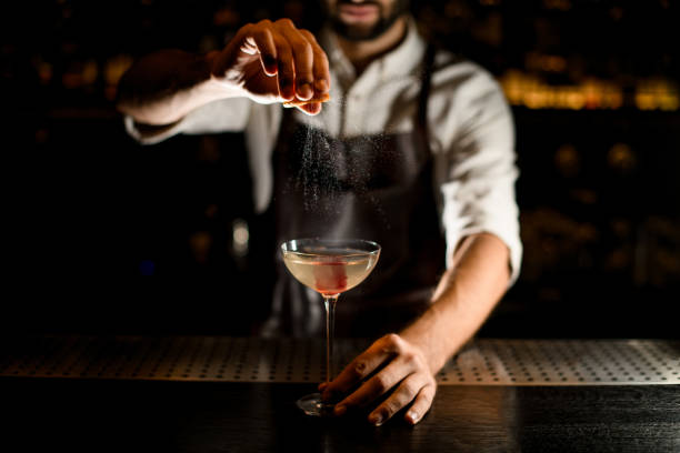 istock Bartender sprinkling alcohol in glass on a counter 1176510426