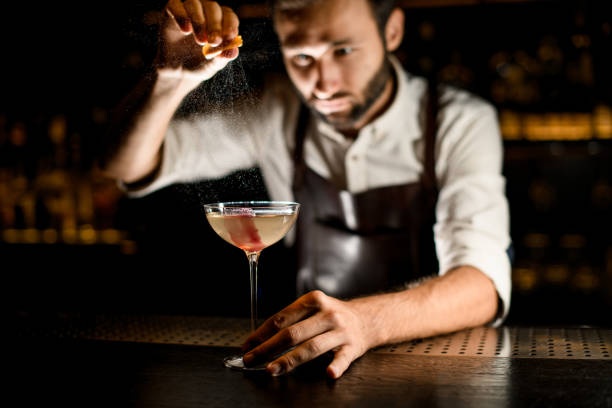 istock Bartender sprinkling cocktail in glass on a counter 1176510557
