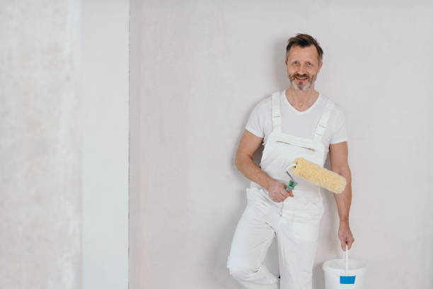 Painter in white dungarees holding a roller stock photo