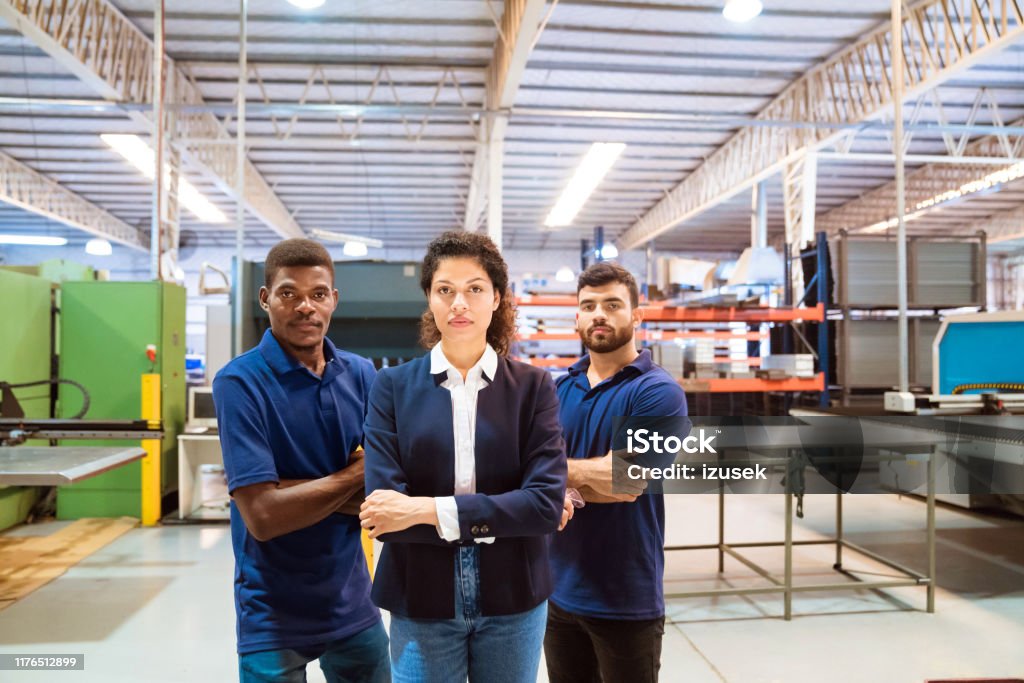 Confident manager and workers in factory Portrait of confident manager and production workers. Expertise are with arms crossed standing in factory. They are related to manufacturing occupation. Serious Stock Photo