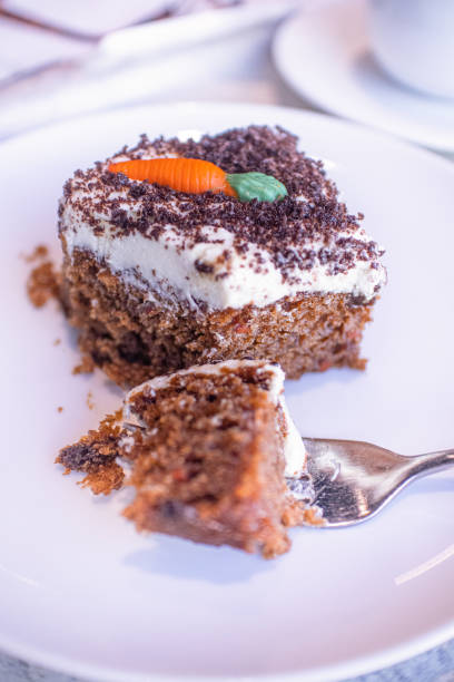 istock Bite sized piece of carrot cake on a fork which has just been sliced off a moist portion sat on a white plate with shallow depth of field. 1176512948