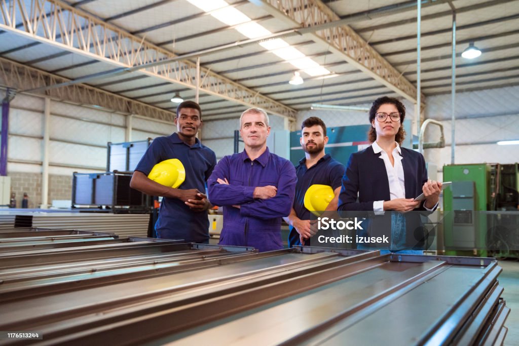 Portrait of confident female inspector and workers Portrait of confident female inspector and production workers. Expertise are related to manufacturing occupation. They are standing in factory. 20-24 Years Stock Photo