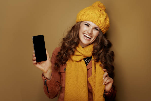 istock woman showing smartphone blank screen and on beige background 1176515358