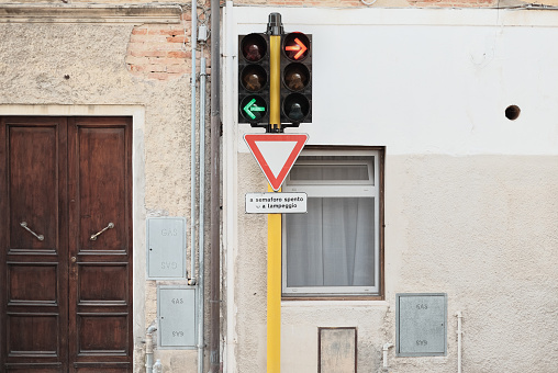 traffic lights at a T-junction in Italy, in front of the facade of a residential building in Tuscany