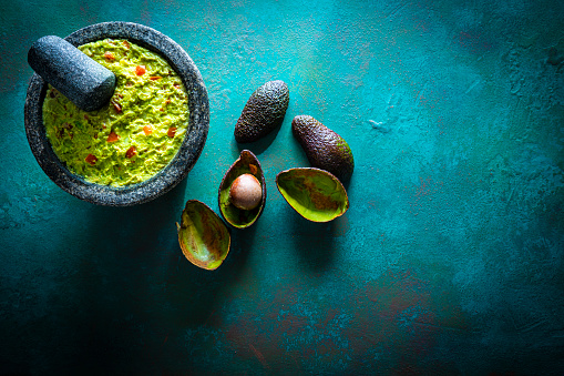 Guacamole prepared in molcajete with avocado on green grunge background