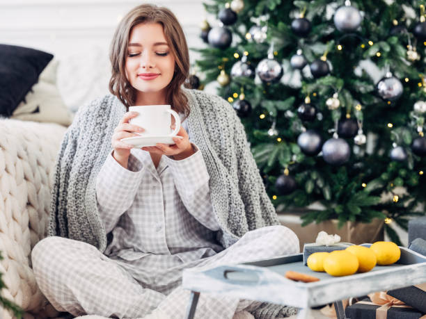 hermosa chica sentada en un ambiente acogedor cerca del árbol de navidad - ropa de dormir fotografías e imágenes de stock