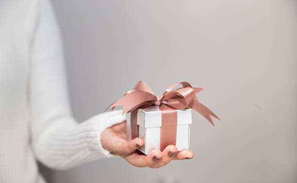 istock Woman hands with white sweater holding a small gift box for special event with copy space. 1176520065