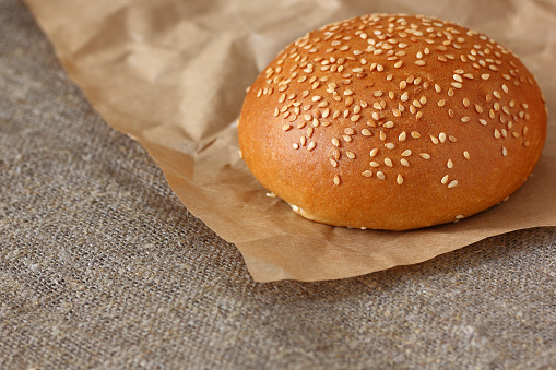 Bun with sesame seeds round on paper wrapping kraft and burlap tablecloth.
