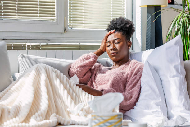 cold and flu. portrait of ill african american woman caught cold, feeling sick and sneezing in paper wipe. closeup of beautiful unhealthy girl covered in blanket wiping nose. healthcare concept. - allergy sneezing cold and flu flu virus imagens e fotografias de stock