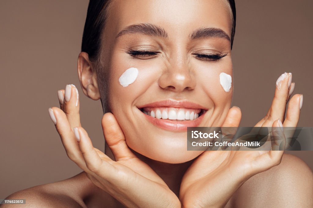 Beautiful woman applying cream on her face Moisturizer Stock Photo