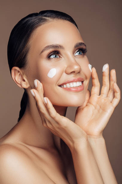 istock Beautiful woman applying cream on her face 1176523596