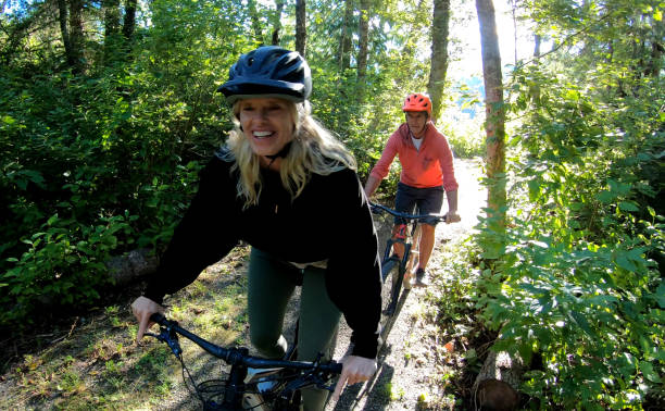 пара горный велосипед через лес на восходе солнца - mature adult vacations action adult стоковые фото и изображения