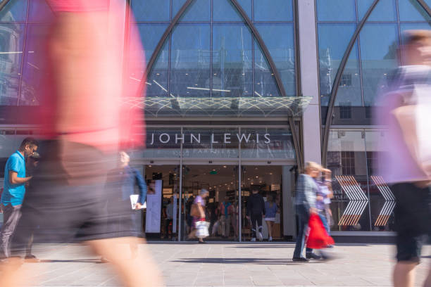 Busy Shoppers in the centre of Cheltenham in The Cotswolds, walking past the new John Lewis & Partners store in the High Street stock photo