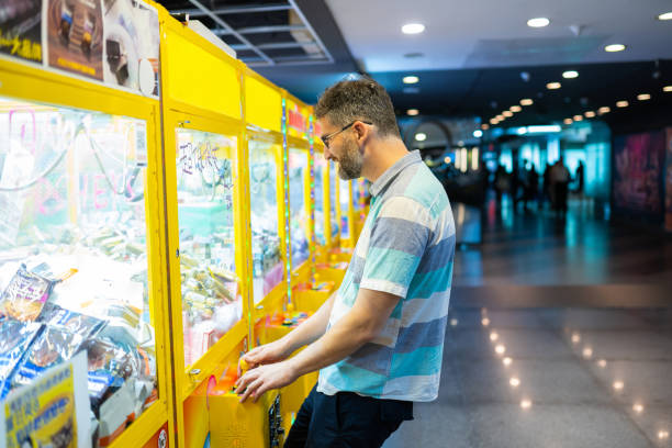 아케이드에서 발톱 게임을하는 남자 - amusement arcade machine toy leisure games 뉴스 사진 이미지