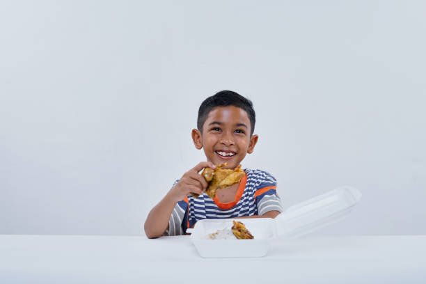 Schoolboy eating fried chicken fastfood on white background