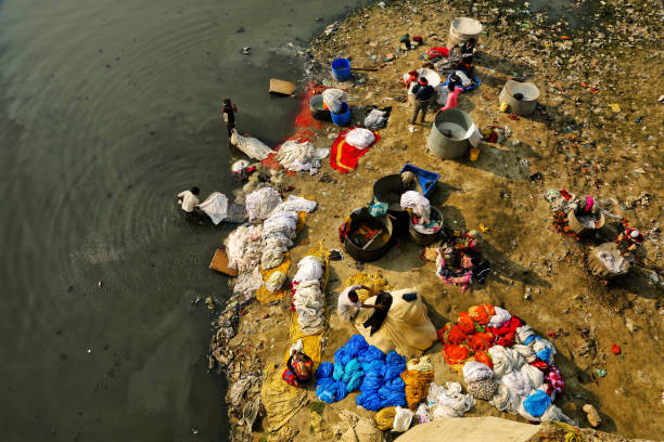 das schmutzige wasser und die reinigung von kleidung durch ein team von wäscherei männer und frauen auf einer wäschebucht (dhobi ghat) am ufer des yamuna river, agra, uttar pradesh, indien - yamuna river stock-fotos und bilder