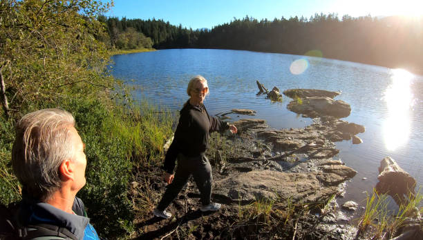 istock Couple hike towards forested lakeshore 1176530137