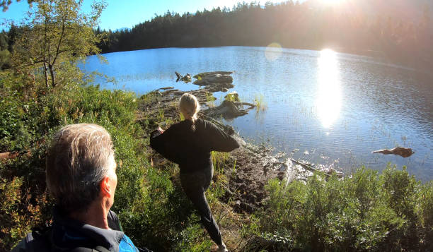 istock Couple hike towards forested lakeshore 1176531005
