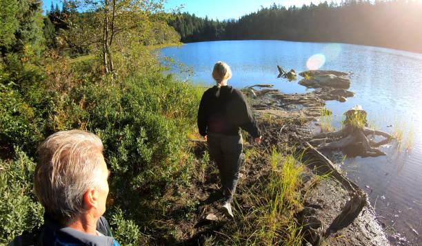 istock Couple hike towards forested lakeshore 1176531029
