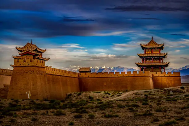 A beautiful sunset light over the Fort Jiayuguan under a moody sky in Gansu Province, Western China.